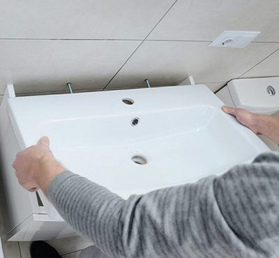 Fitter installing a bathroom sink to wall