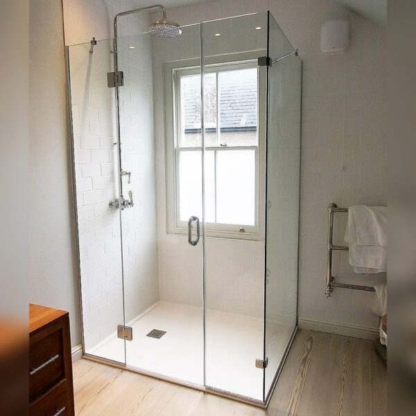 Large frameless hinged shower door between 2 inline panels with side return by Room H2o