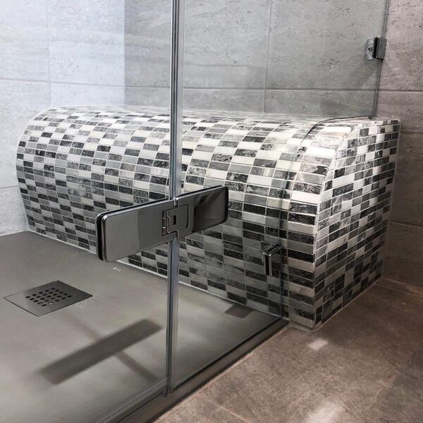 Room H2o bespoke frameless shower screen shaped around a tiled shower seat