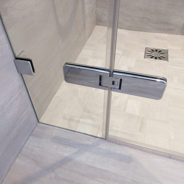 Frameless glass shower door with inline panel with chrome wall brackets and hinges